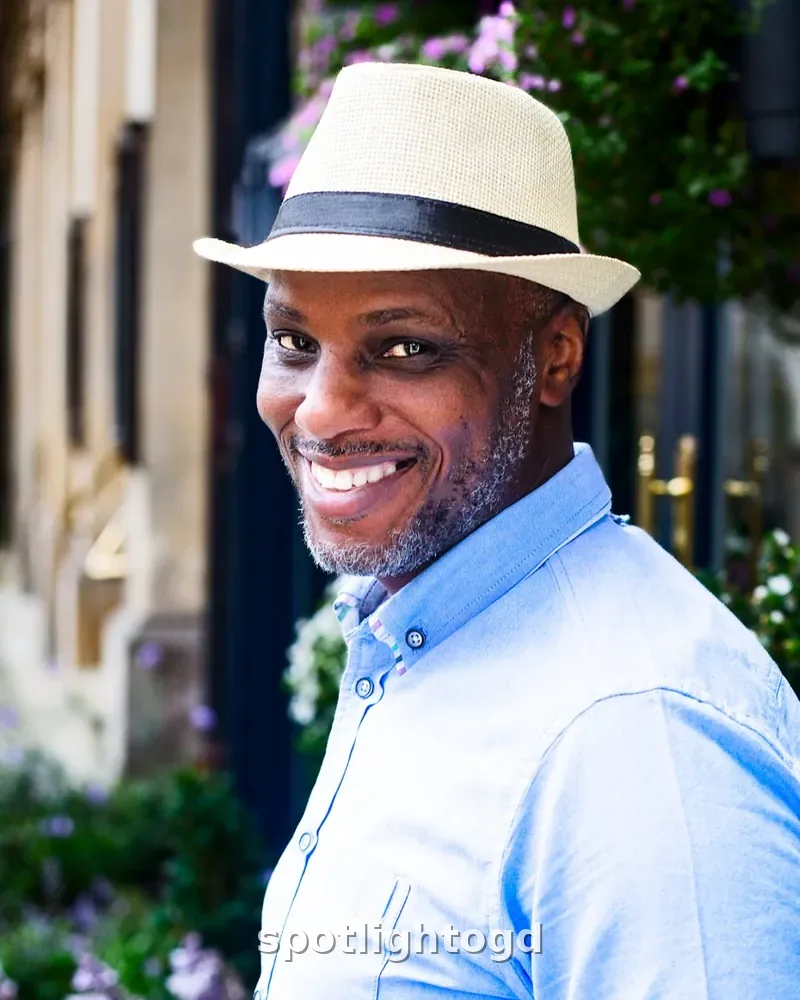 O.G. Dawodu smiling warmly in a pale straw hat and light blue shirt